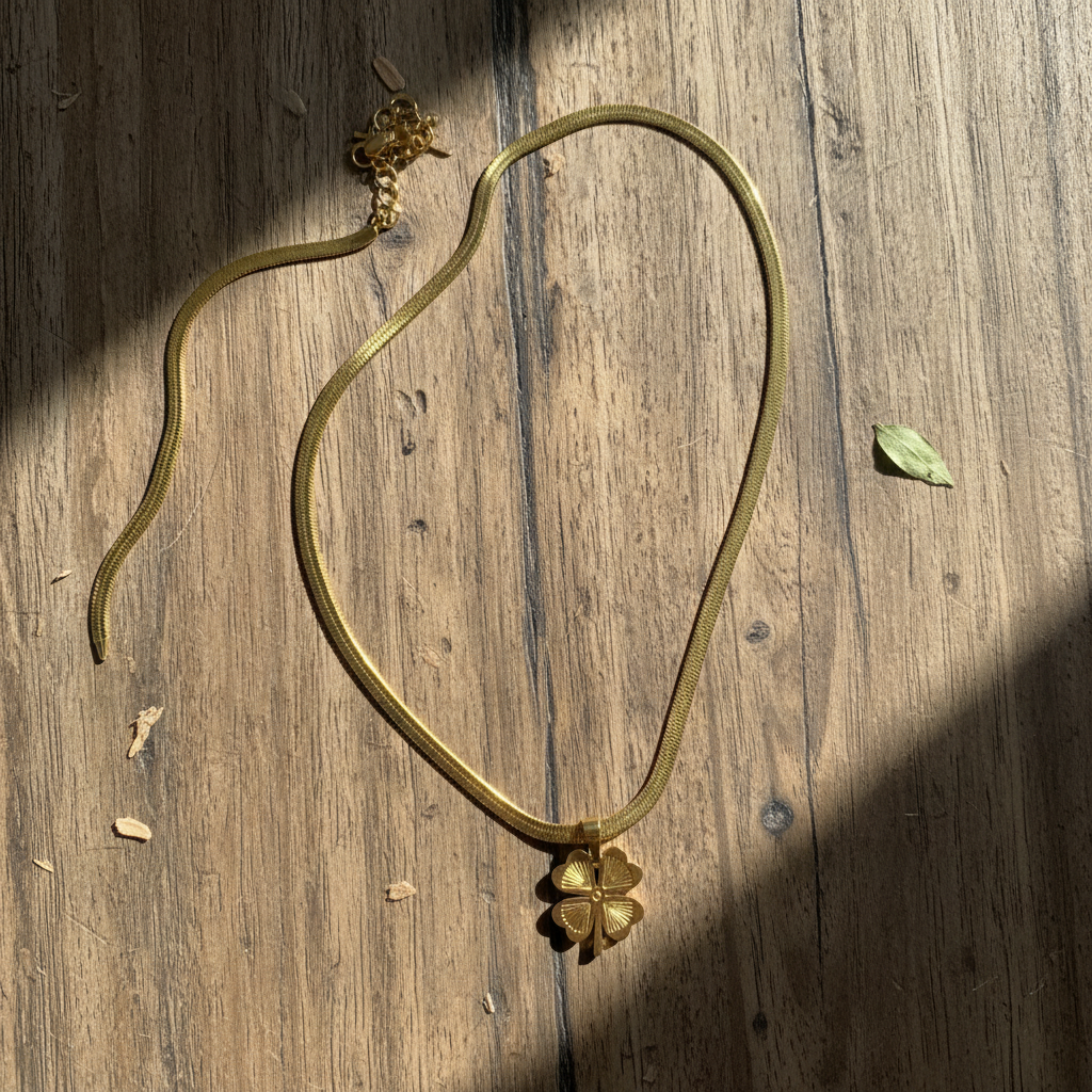 Gold clover necklace on wooden table with natural grain texture and window light"