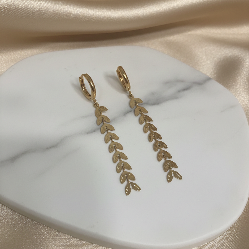 Gold leaf drop earrings with cascading botanical design on white marble