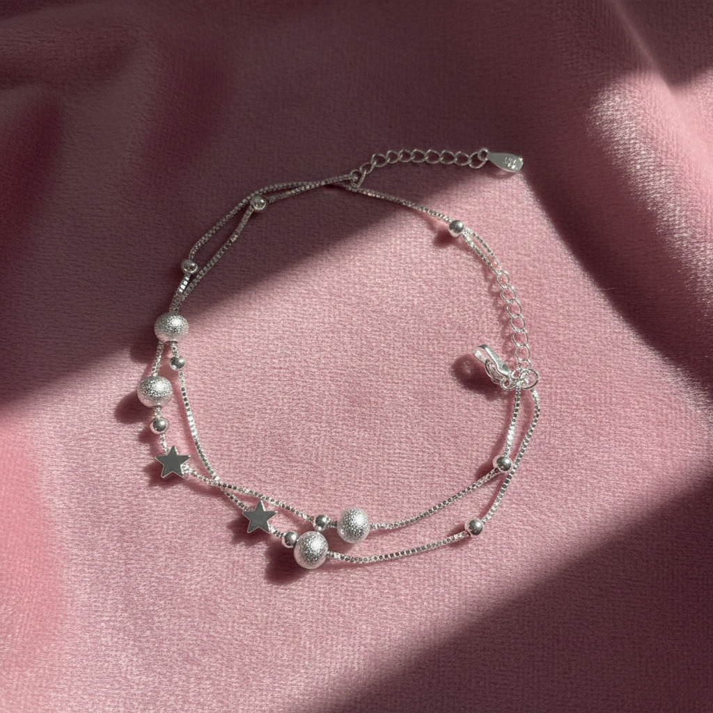 Silver star anklet arranged on pink velvet fabric, luxury jewelry presentation"